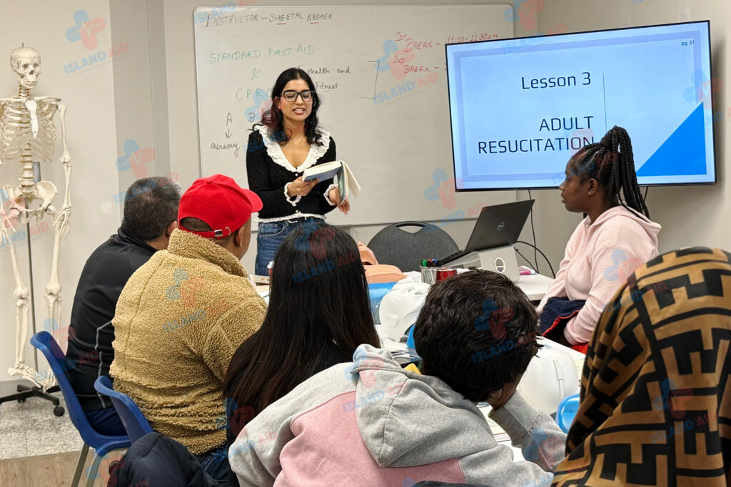 Trainer giving a first aid class at IslandAid, demonstrating techniques to a group of students